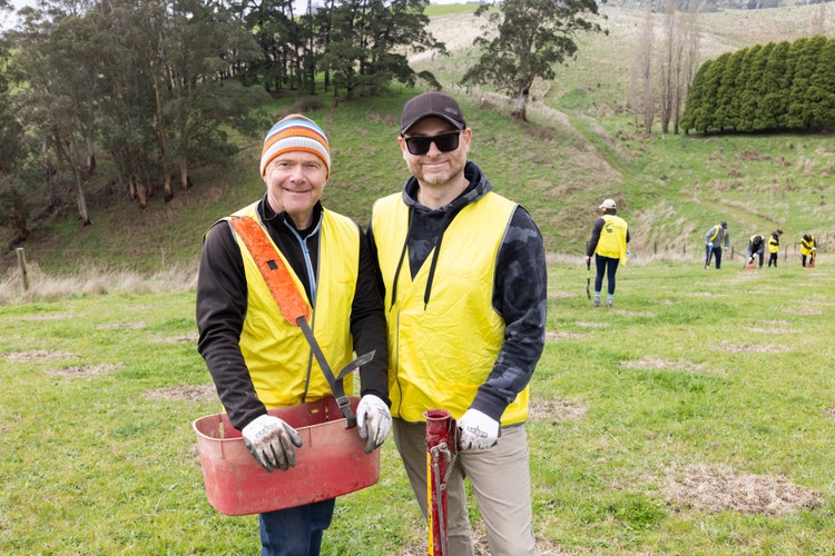 Two men in high-vis in front of a forest